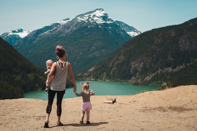 Žena s dvoma malými deťmi stojí na skale a pozoruje more.jpg